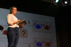Annika während ihres Vortrages auf der Bühne mit Präsentation im Hintergrund