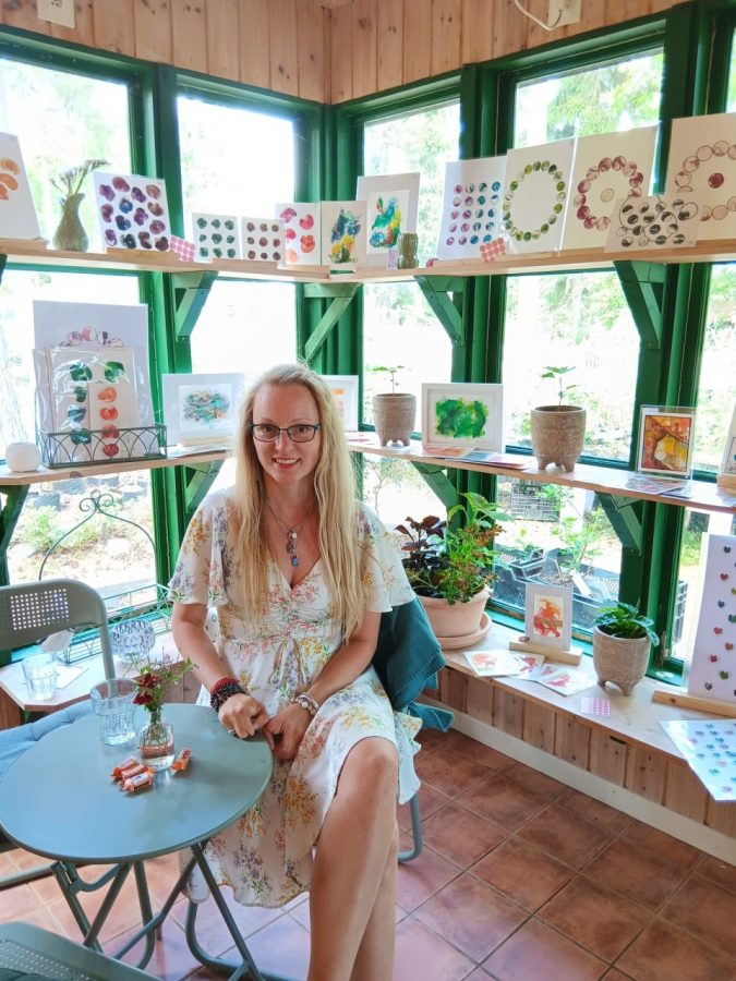 Foto von Scientific Illustrator Dr. Daria Chrobok, wie sie vor ihrer abstrakten Kunst in ihrer Ausstelung sitzt.